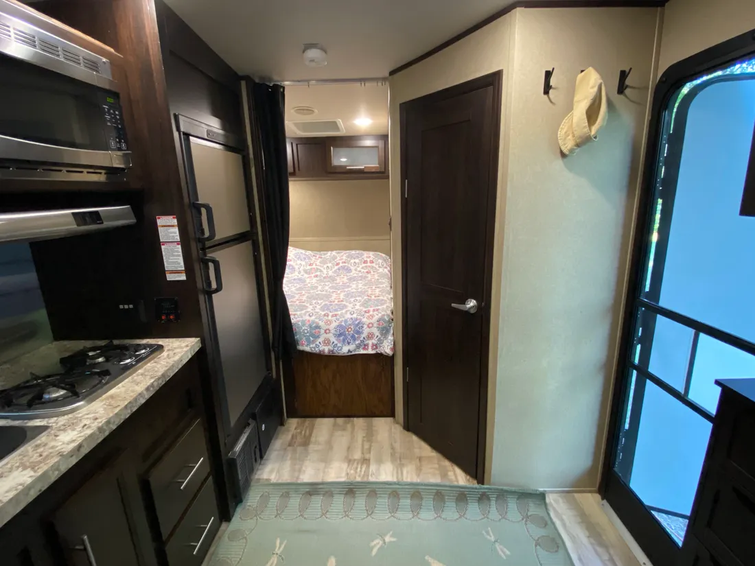 Inside the trailer: kitchen with stove, microwave and fridge, bedroom beyond